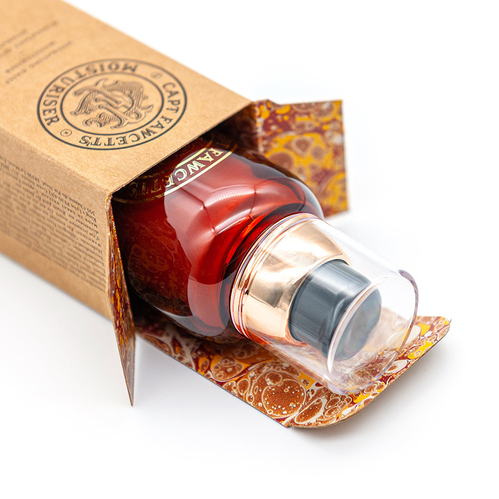 Red serum bottle with gold cap in a decorative box on a white background