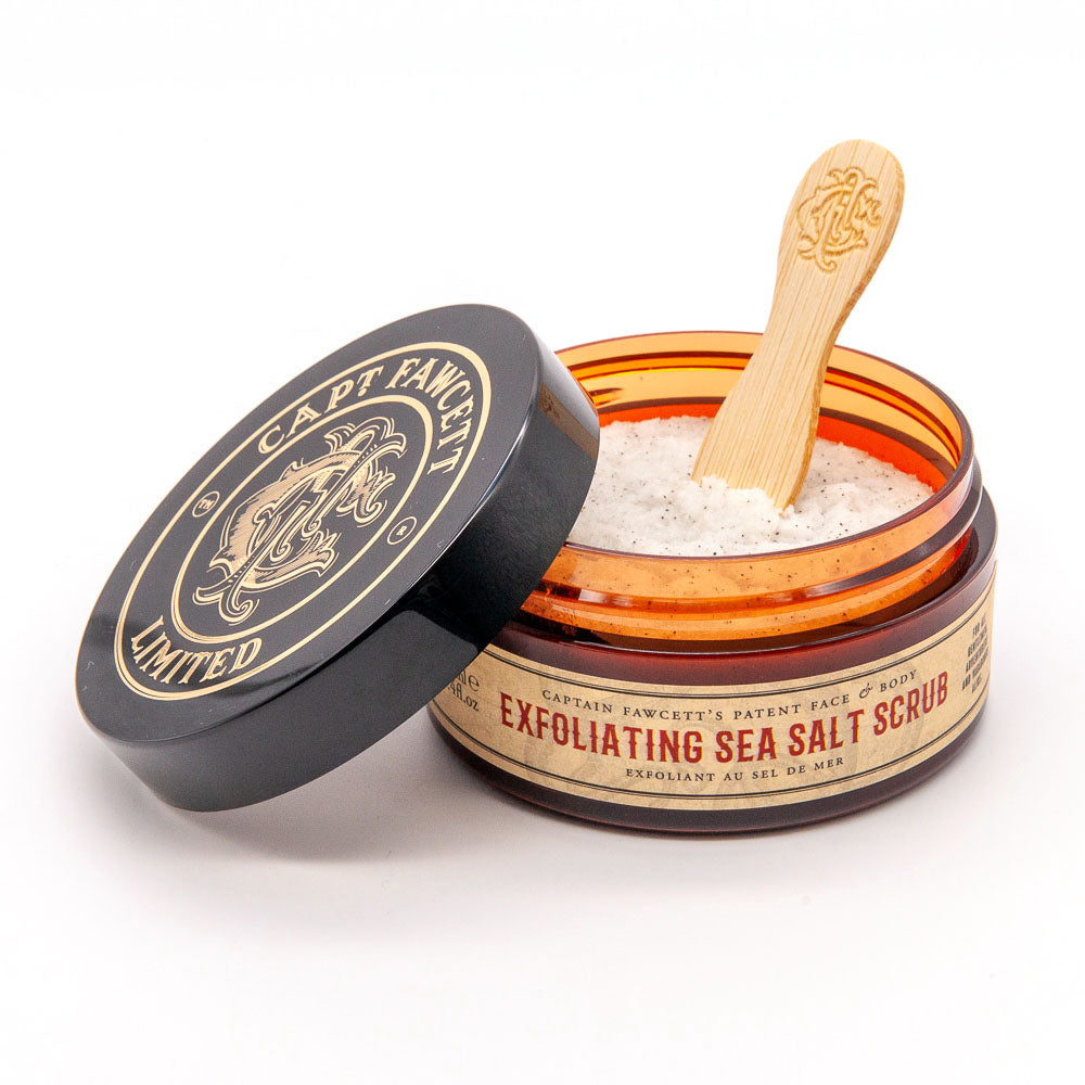 Open jar of Captain Fawcett Exfoliating Sea Salt Scrub with a wooden spoon on a white background