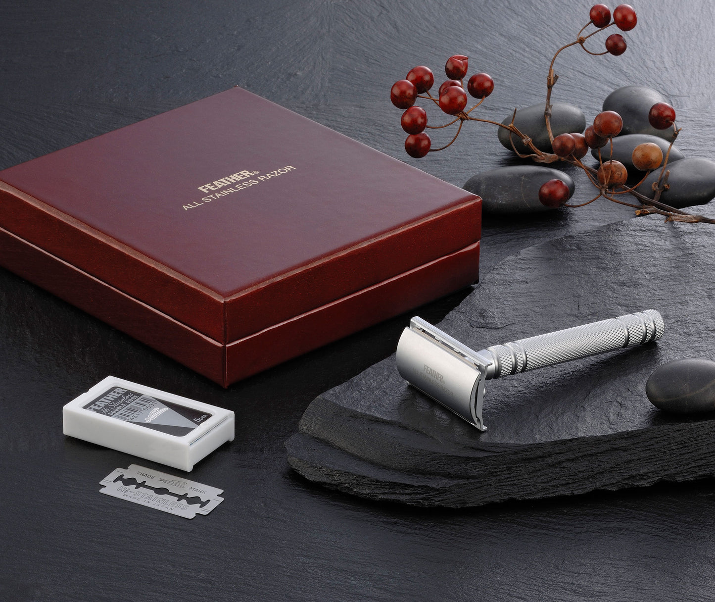 Feather All Stainless Safety Razor AS-D2 displayed with its premium wooden box, blades, and a natural slate background for an elegant presentation.