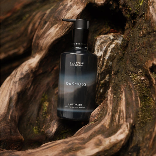 Oakmoss Hand Wash pump bottle nestled against weathered tree roots
