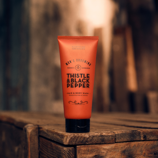 Orange Thistle & Black Pepper Hair & Body Wash tube on stacked wood