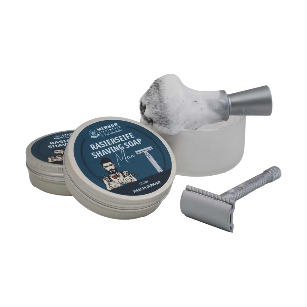 Merkur Men's Shaving Soap lathered in a frosted shaving bowl, paired with a safety razor and brush, demonstrating its rich lather.