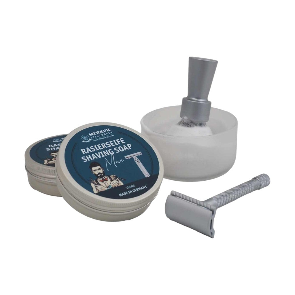 Merkur Men's Shaving Soap with a lathered shaving brush, an aluminum tin, and a classic safety razor, illustrating its creamy foam.