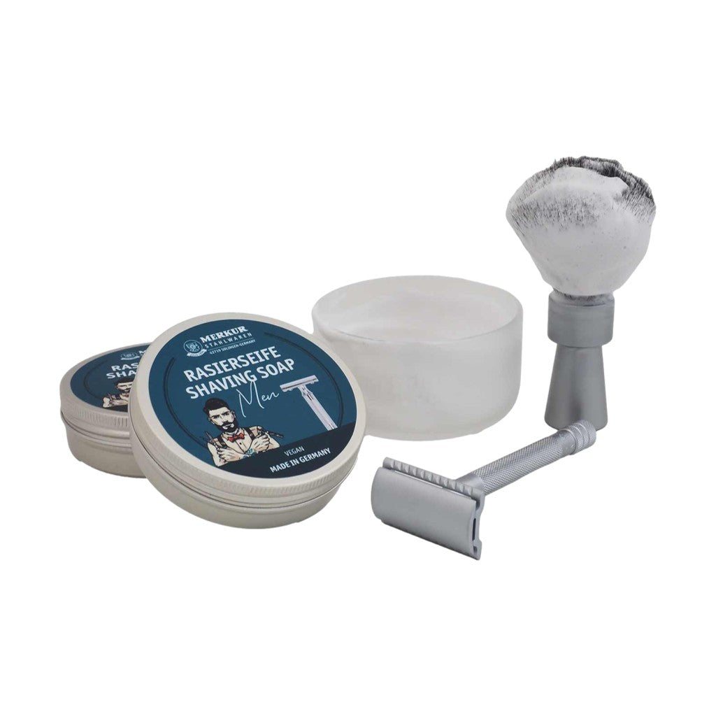 Merkur Men's Shaving Soap in an aluminum tin, accompanied by a shaving brush, showcasing a classic grooming product setup.