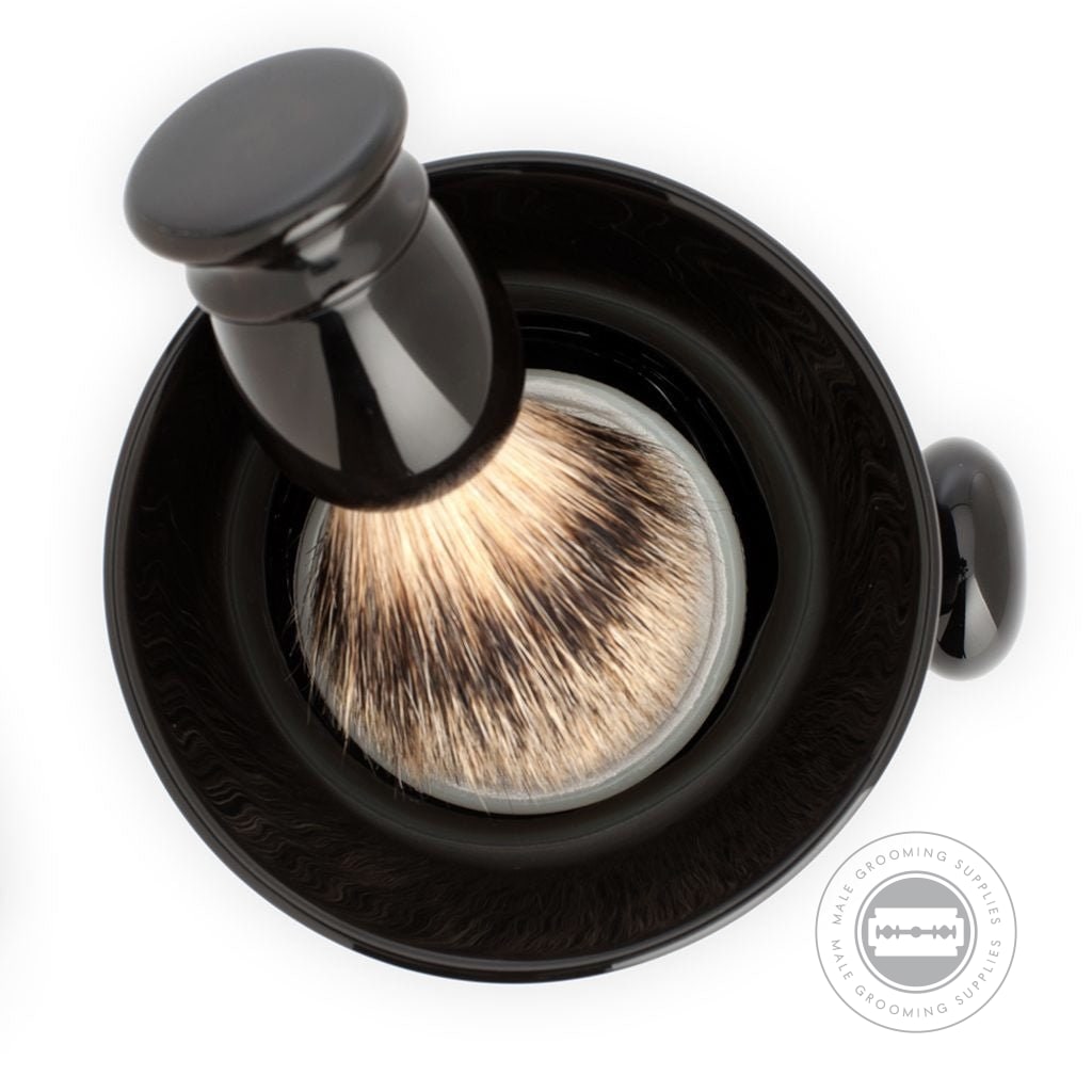 Top view of the MÜHLE Porcelain Black Shaving Mug with a shaving brush resting inside, highlighting the mug’s deep black finish and practical knobby handle.