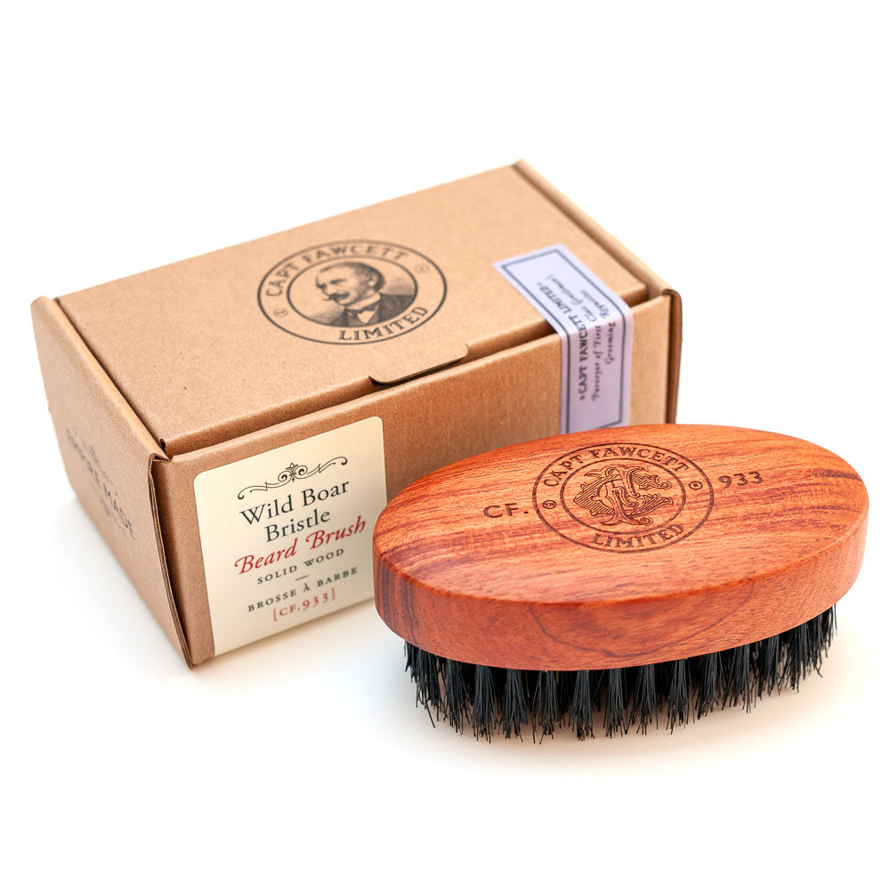 Wooden beard brush with black bristles and branded packaging on a white background