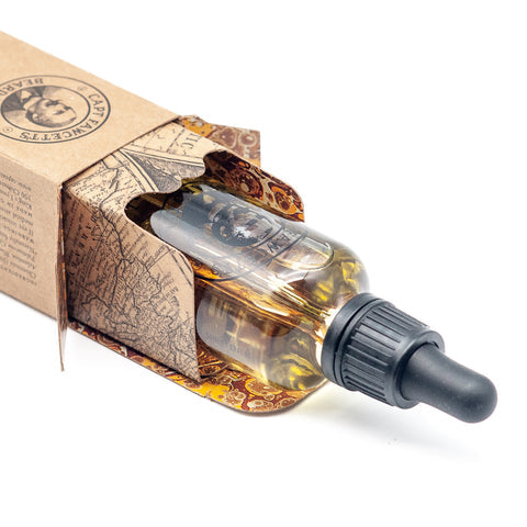 Clear glass dropper bottle with amber liquid in a decorative box on a white background