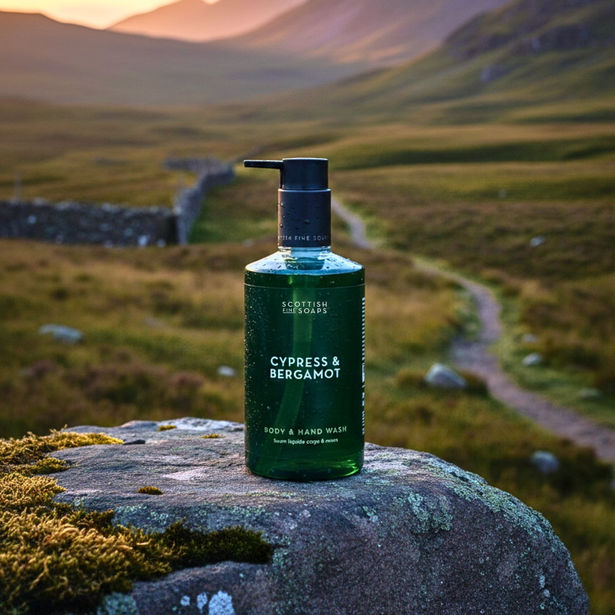 Green Cypress & Bergamot Body & Hand Wash bottle on a mossy rock in a mountain landscape