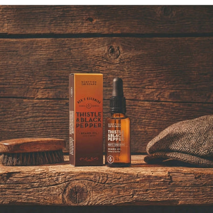 Thistle & Black Pepper Beard Oil dropper bottle with its box beside a beard comb
