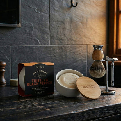 Thistle & Black Pepper shaving soap in a ceramic bowl with bamboo lid beside a basin
