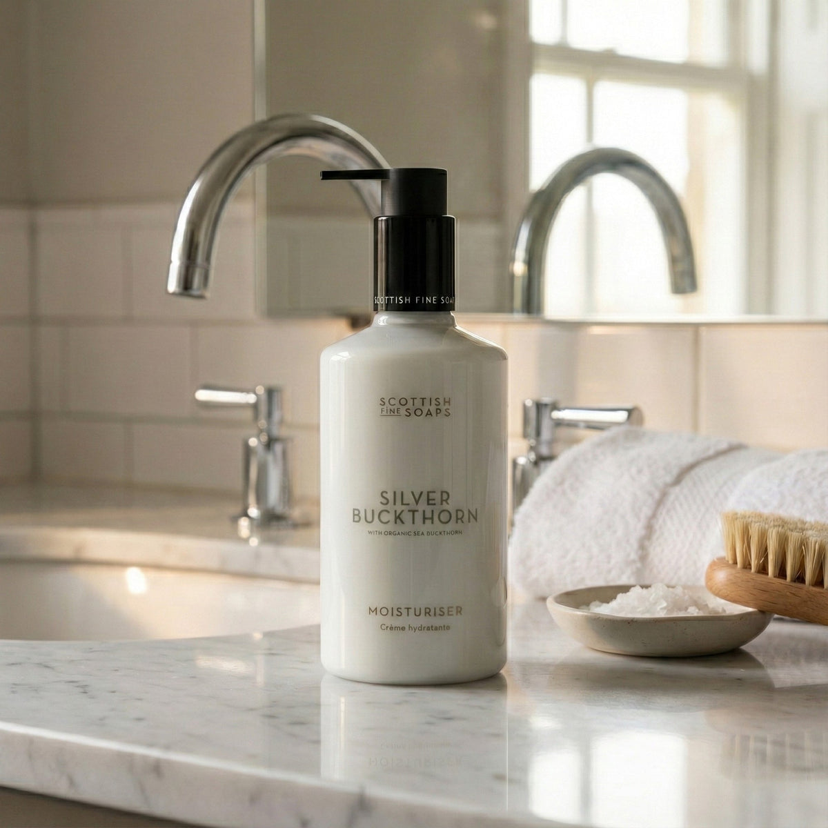 Silver Buckthorn Moisturiser pump bottle beside a bathroom basin and towels