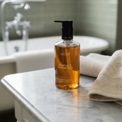 Amber Santal & Patchouli Body & Hand Wash bottle beside a basin and folded towel