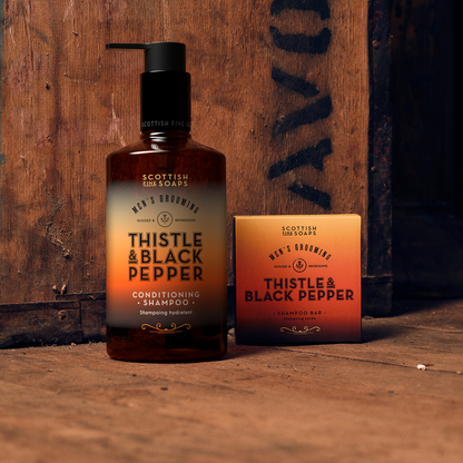 Thistle & Black Pepper All-in-One Wash pump bottle with a boxed Shampoo Bar on wood