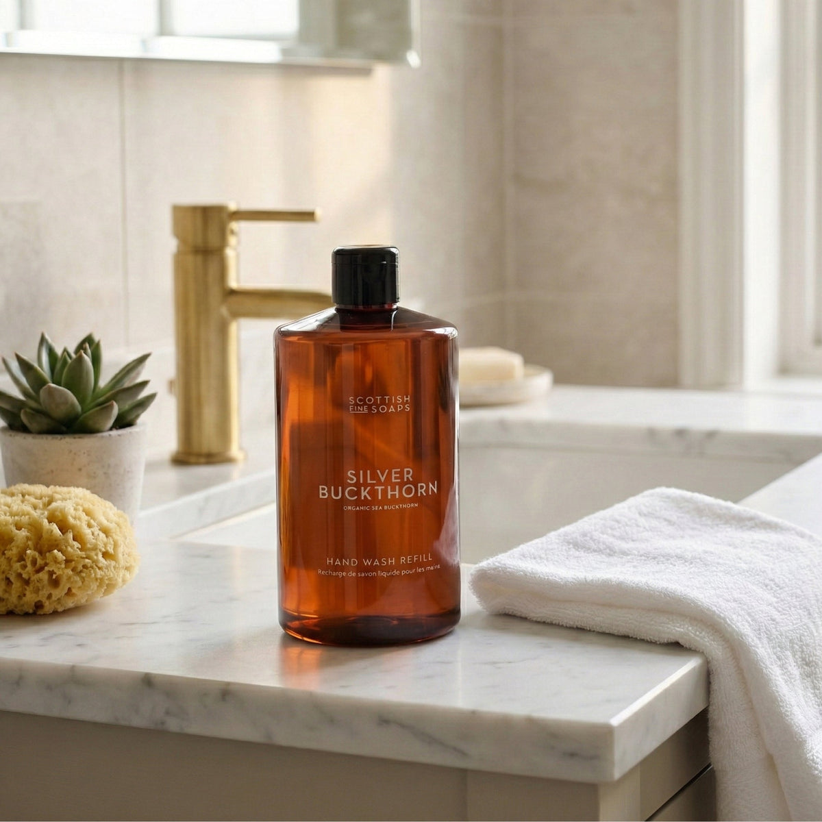 Silver Buckthorn Hand Wash refill bottle on a bathroom ledge beside a folded towel