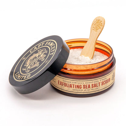 Open jar of Captain Fawcett Exfoliating Sea Salt Scrub with a wooden spoon on a white background