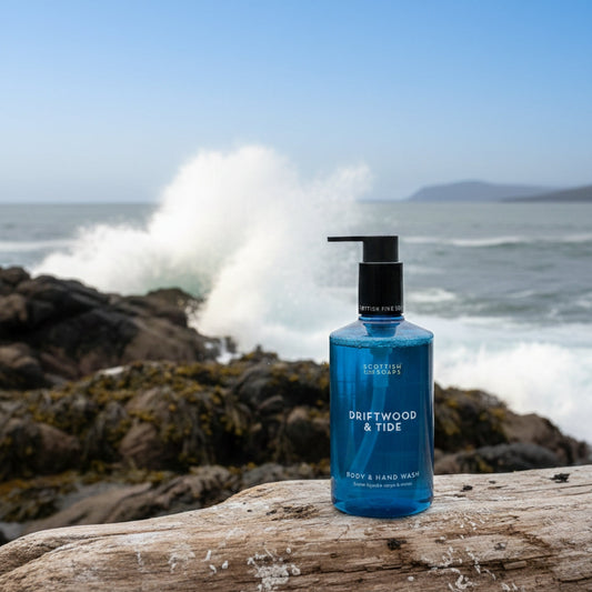 Blue Driftwood & Tide Body & Hand Wash bottle on rocks beside breaking coastal waves