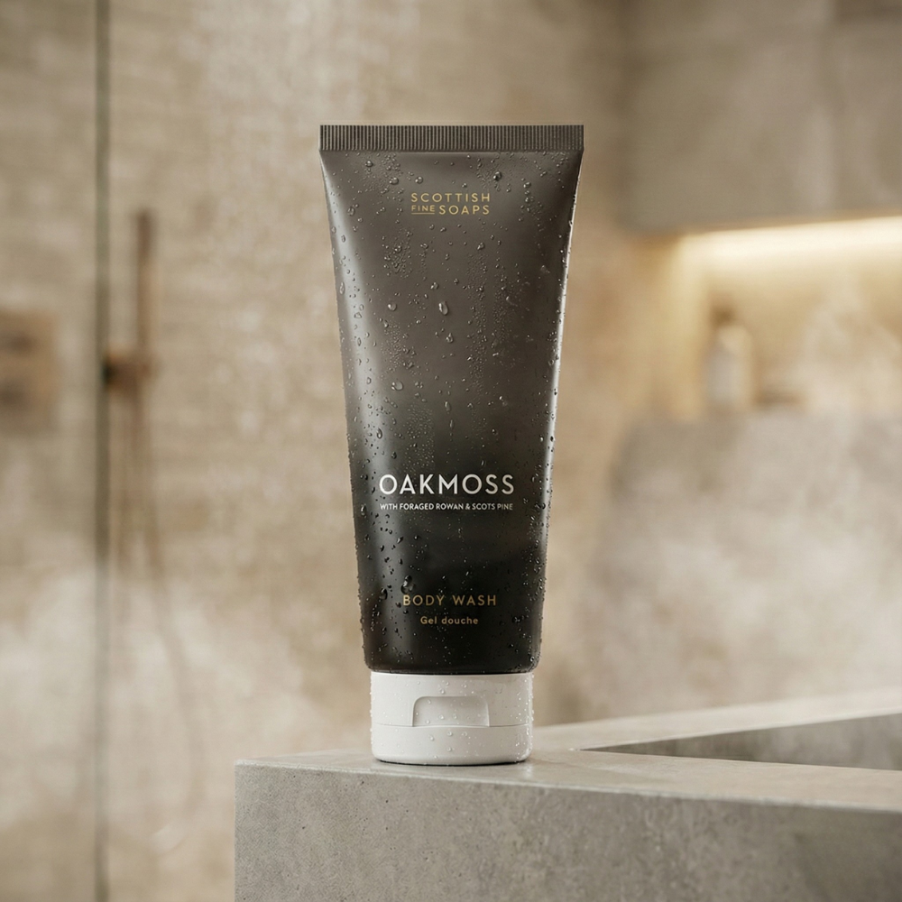 Oakmoss Body Wash tube hanging against a stone shower wall