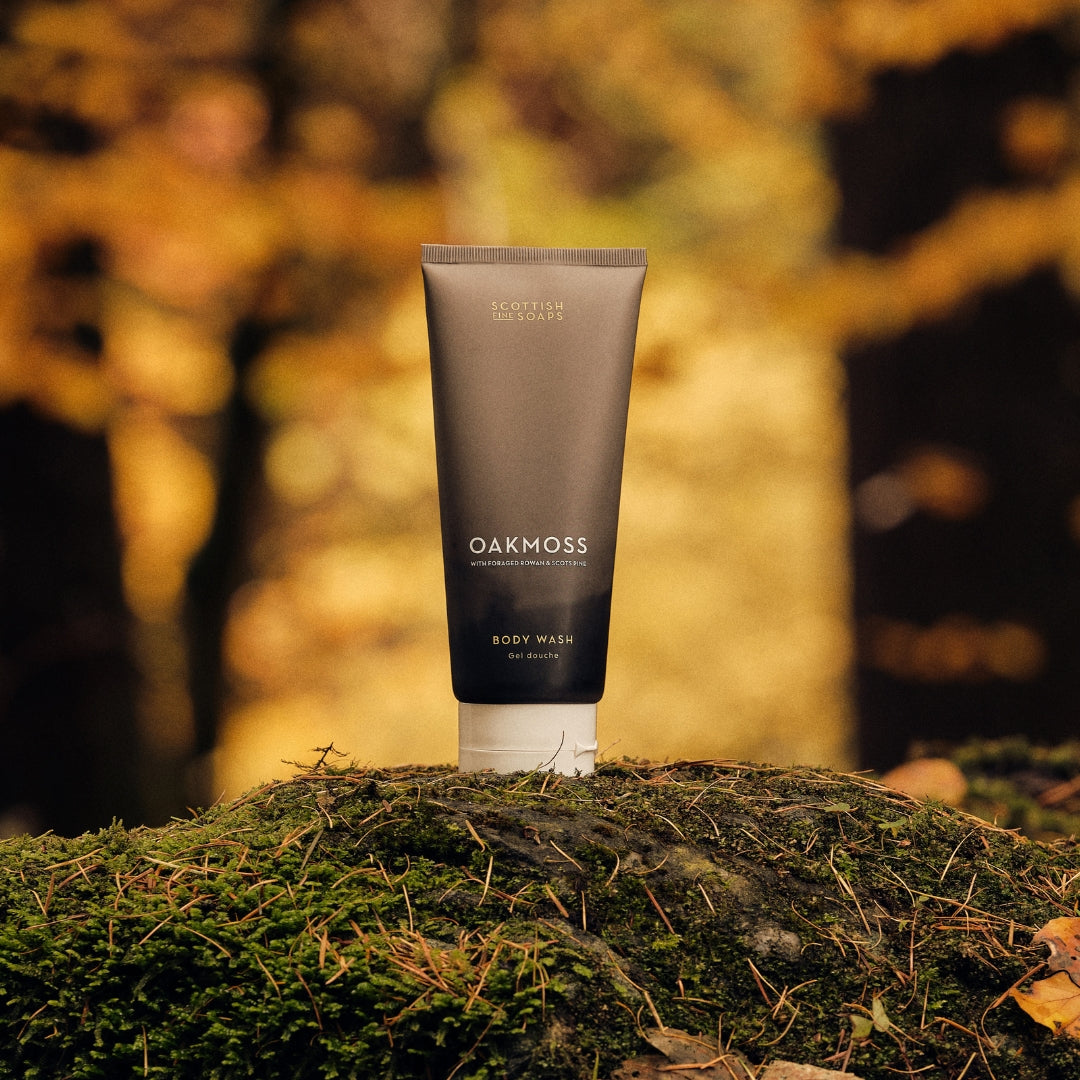 Oakmoss Body Wash tube standing on moss with autumn leaves behind it