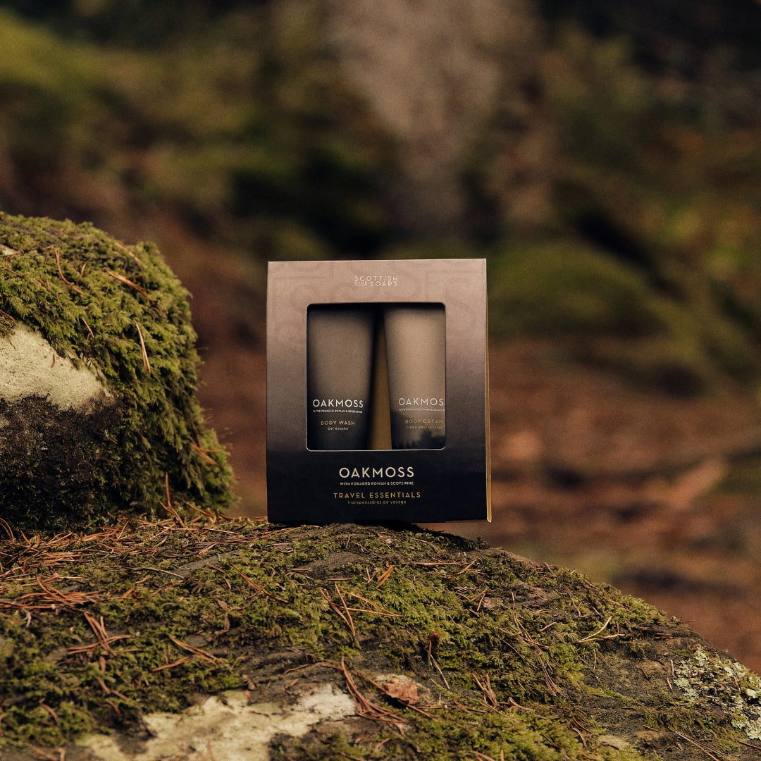 Boxed Oakmoss Travel Essentials set standing on a moss-covered log