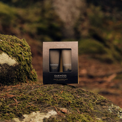 Boxed Oakmoss Travel Essentials set standing on a moss-covered log
