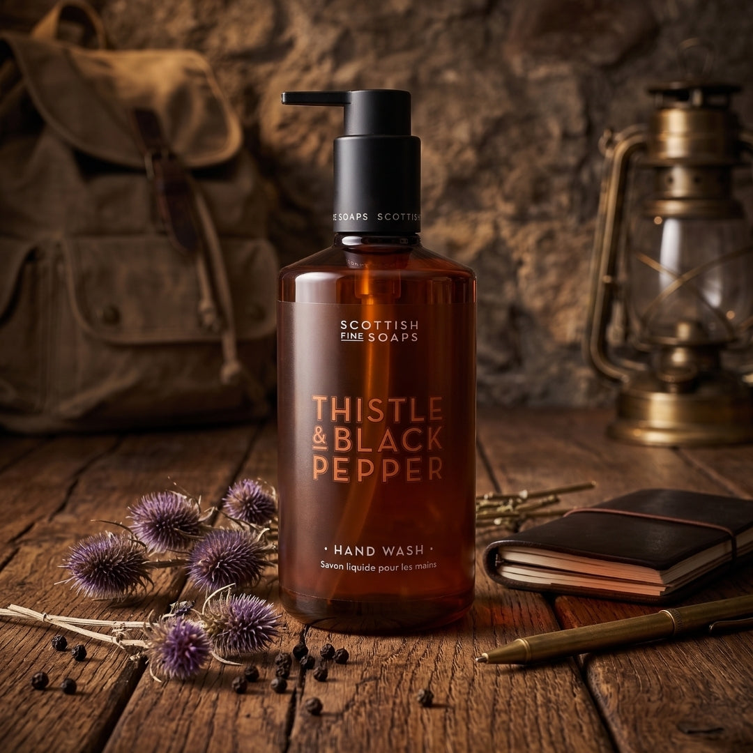 Thistle & Black Pepper Hand Wash pump bottle on wood beside thistles and grooming accessories