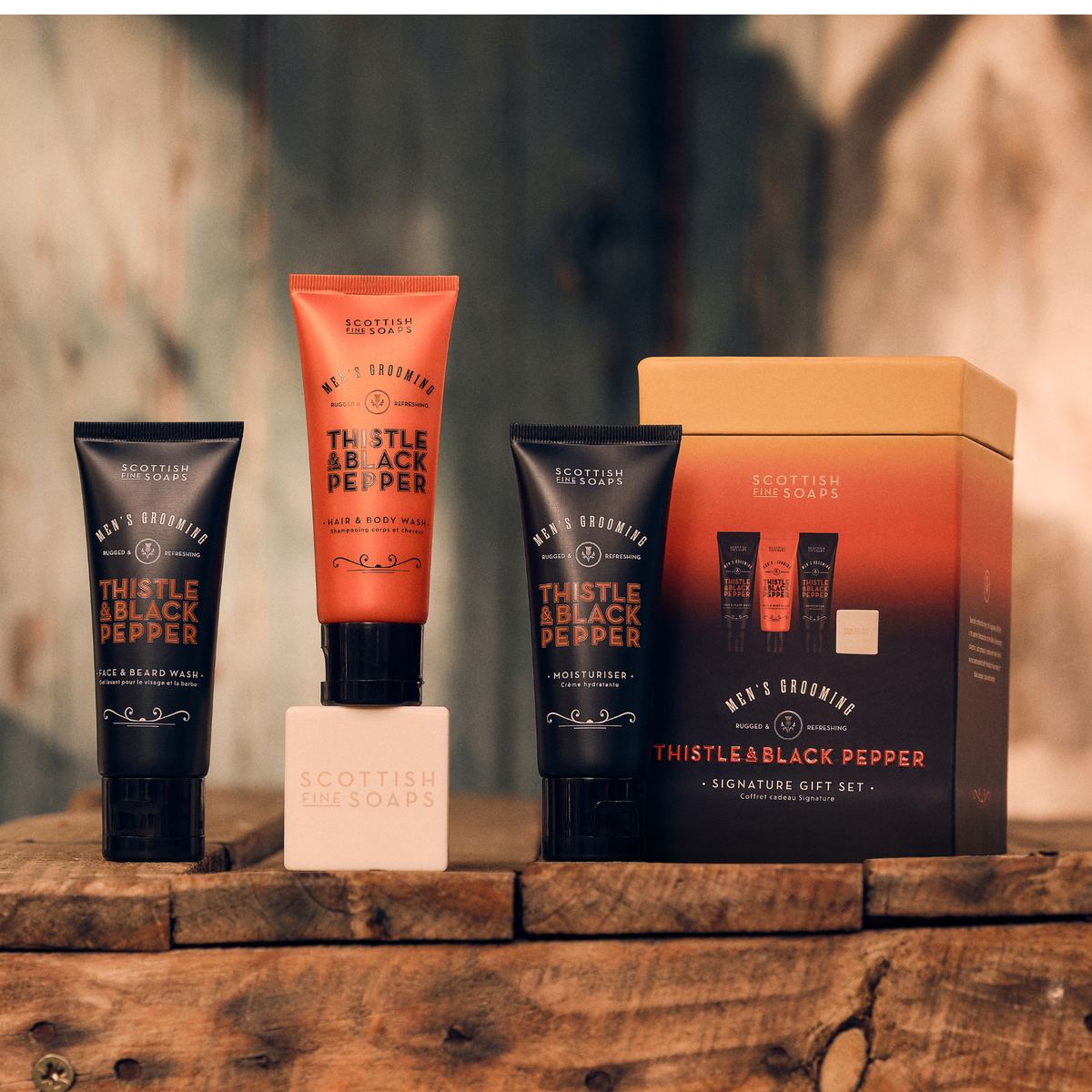 Thistle & Black Pepper Signature Gift Set showing three tubes and a soap bar on wood