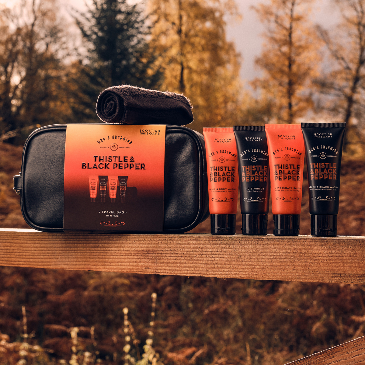 Thistle & Black Pepper black travel washbag with four grooming tubes in a woodland setting