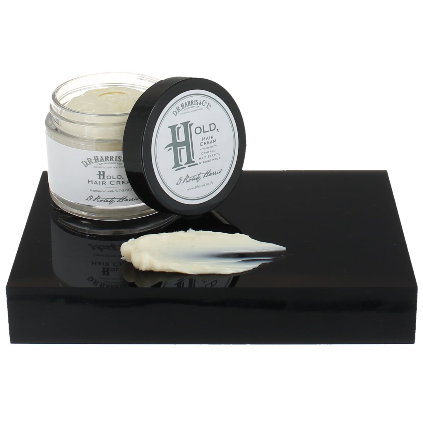 Hair cream jar with lid on a black platform against a white background