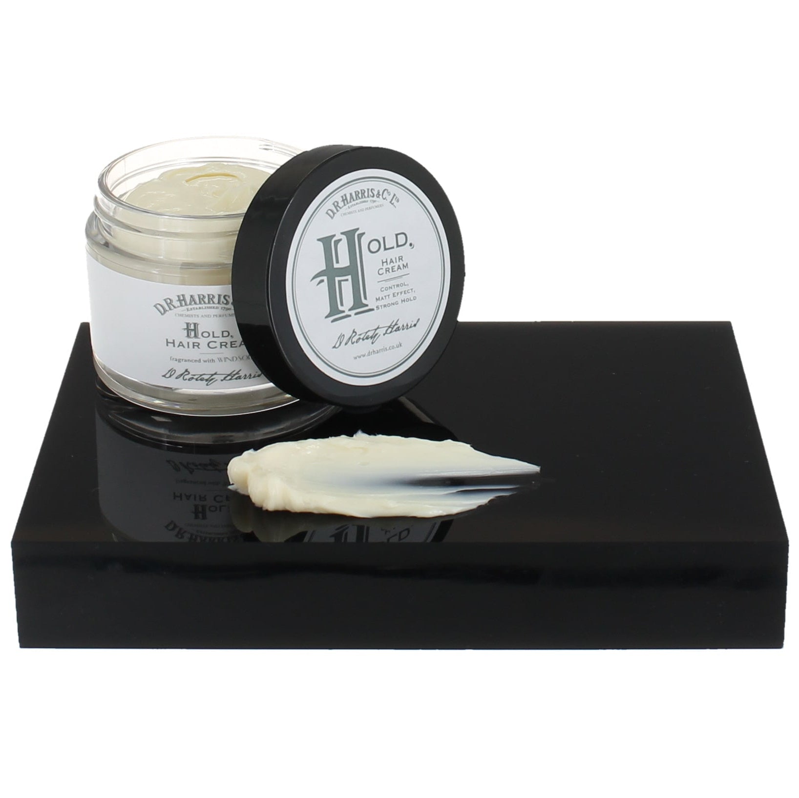 Hair cream jar with lid on a black platform against a white background