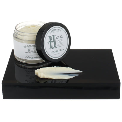 Hair cream jar with lid on a black platform against a white background