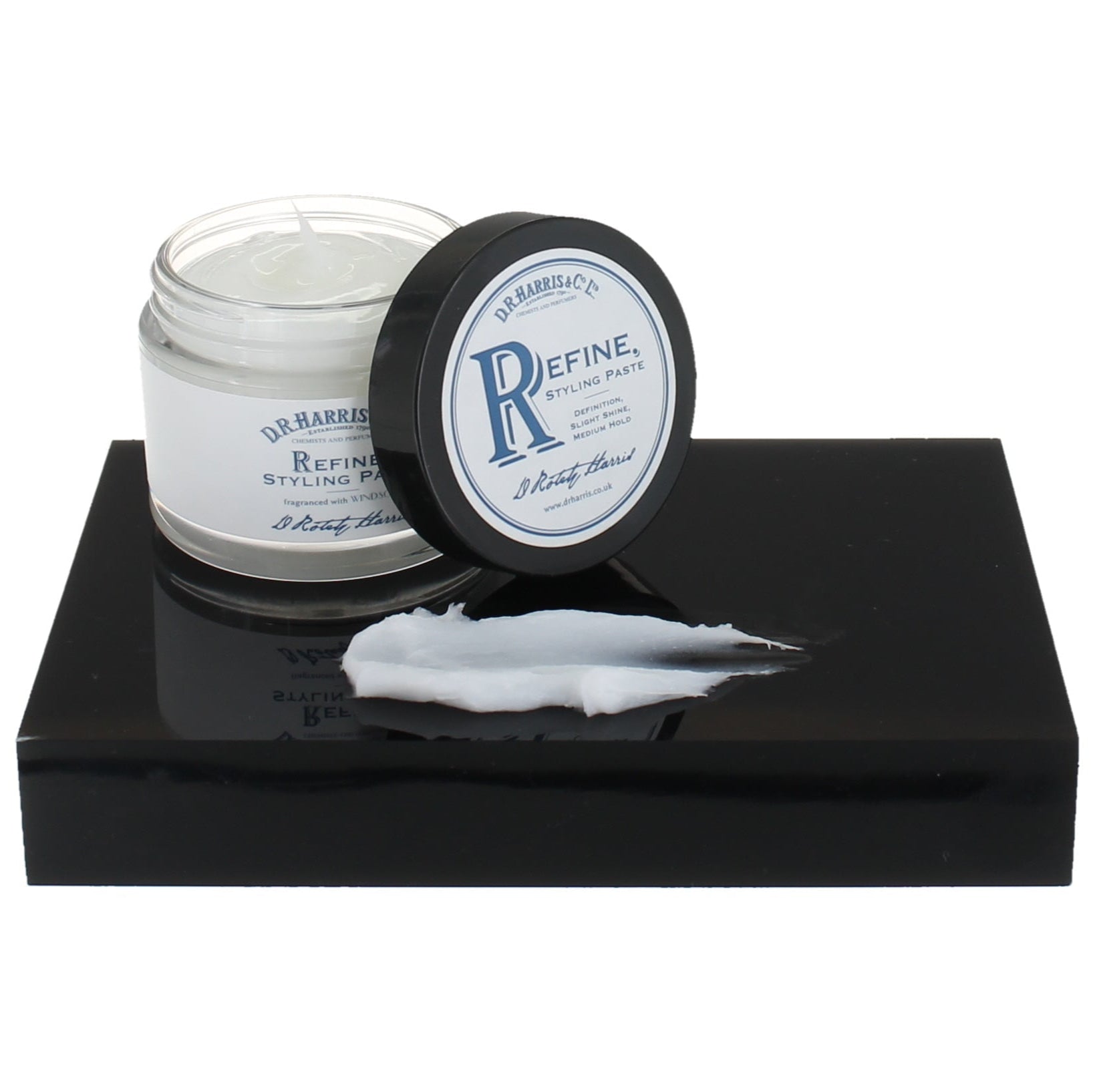 Jar of cream with a black lid on a white background.