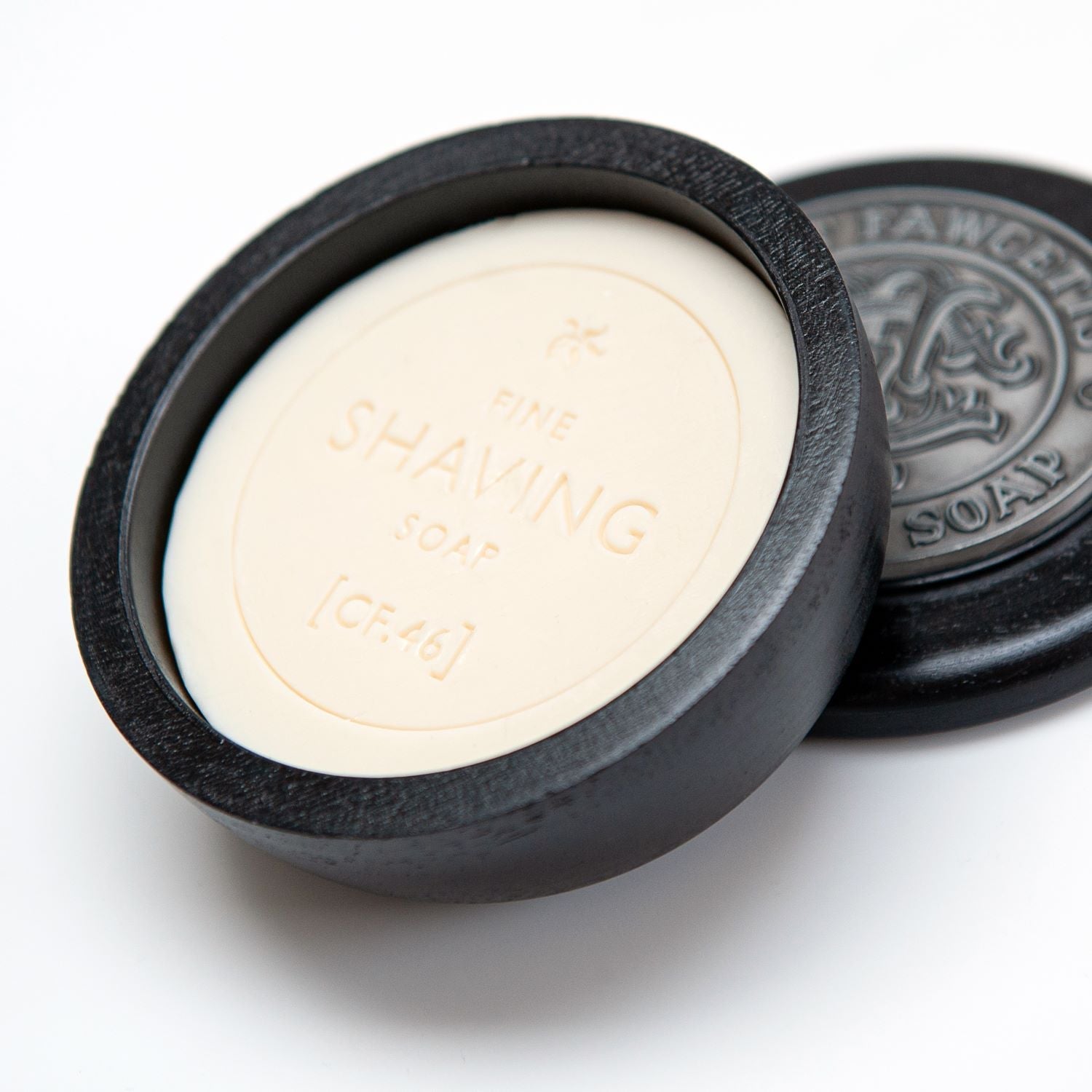 Bar of shaving soap in a black wooden container on a white background